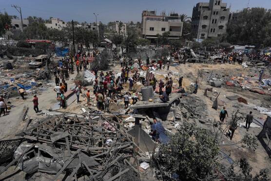 TOPSHOT - Palestinians look at the debris of destroyed tents and make shift housing structures following an Israeli military strike on the al-Mawasi camp for internally displaced people (IDP), near the city of Khan Yunis, southern Gaza Strip on July 13, 2024, in which killing 71 people were killed.    Al-Mawasi had been declared a safe zone by Israel as it pursues its military offensive in other parts of the Gaza Strip in response to the October 7 Hamas attacks. (Photo by Bashar TALEB / AFP)